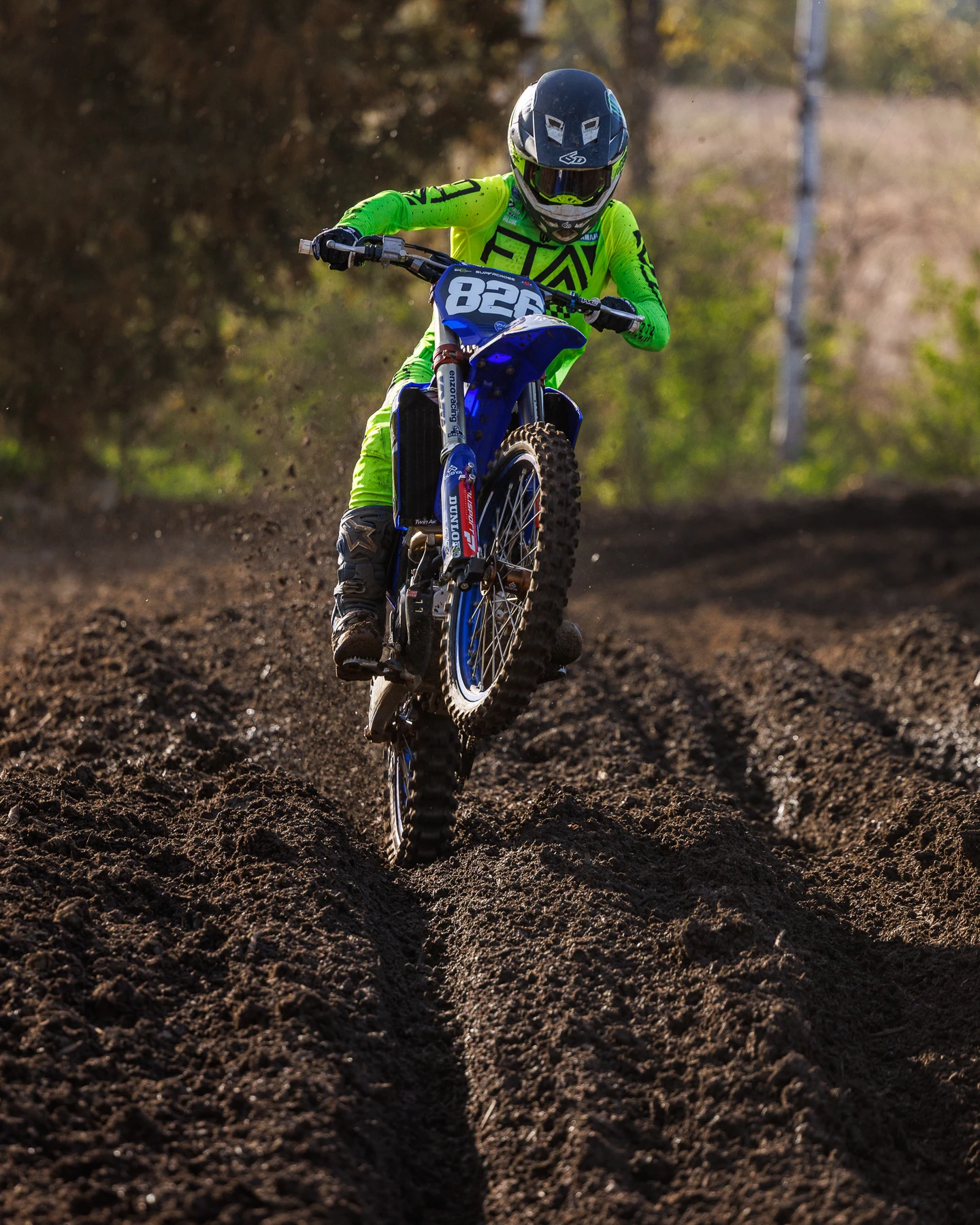 Motocross rider in neon green jumping blue dirt bike.